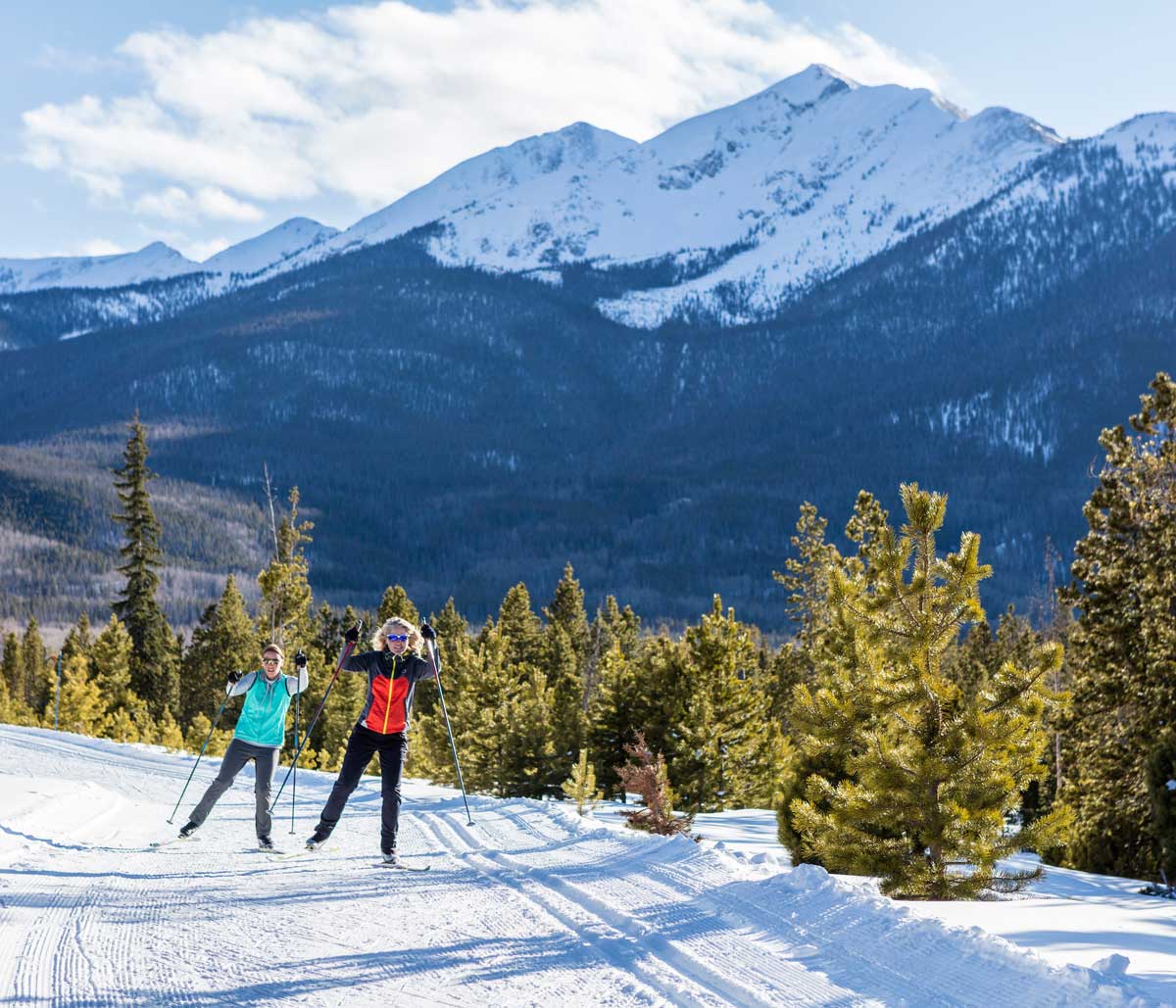 Two female nordic skiers coming around a curve on the Frisco Nordic ski trails